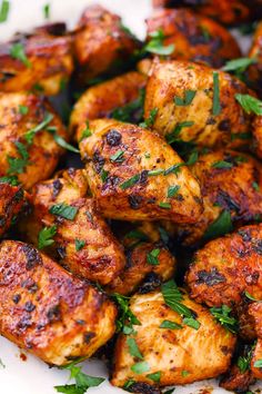 a plate full of grilled chicken with parsley on top