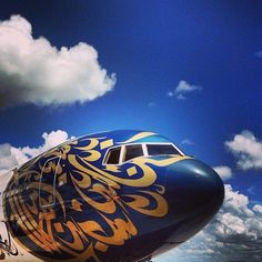 an airplane painted with gold and blue on the tarmac at an airport, under a cloudy sky