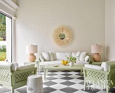 a living room filled with white furniture next to a large open window and a checkered floor