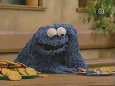 a cookie monster sitting at a table with cookies in front of him