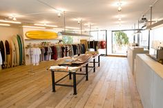 the inside of a clothing store with wooden floors and surfboards hanging on the walls