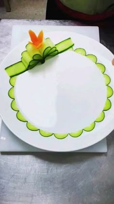 a white plate topped with an orange flower and green ribbon on top of a table