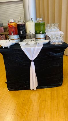 a black table topped with lots of food on top of a hard wood floored floor