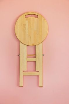 a wooden stool on a pink wall