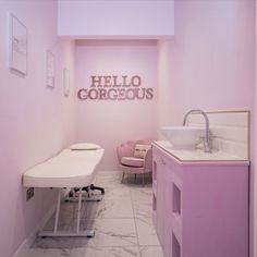 a bathroom with a sink, mirror and pink chair next to the wall that says hello gorgeous