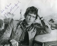 an old black and white photo of a man leaning on a car with his hand on his head