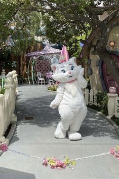 a large white rabbit standing on its hind legs in the middle of a walkway next to a house