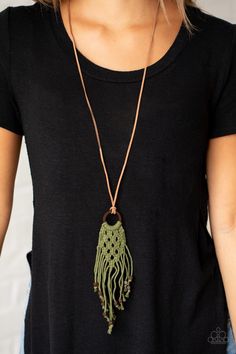 a woman wearing a black shirt and a necklace with a green tassell hanging from it