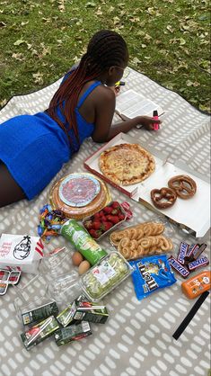 a woman is laying on the ground with food and snacks in front of her,