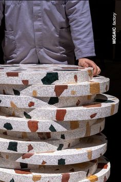 a man standing next to a stack of white plates