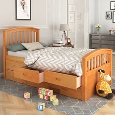 a wooden bed with drawers underneath it in a room filled with toys and pictures on the wall