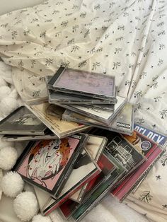 a pile of cds sitting on top of a bed covered in white pom - poms