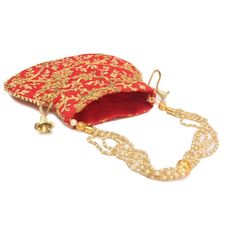 a red and gold purse sitting on top of a white table next to a bell