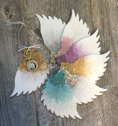 two white flowers with gold and green accents on them sitting on a wooden table next to each other