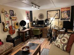 a living room filled with lots of furniture and guitars on the wall next to a coffee table