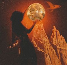 a woman standing in front of a disco ball on top of a mountain at night