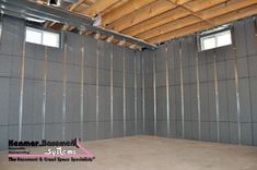 an unfinished room with two windows and wooden beams on the ceiling, along with walls that have been insulated