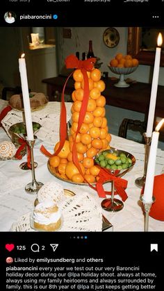 a table topped with oranges next to candles and other food on top of it