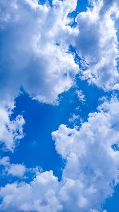 the airplane is flying high in the blue sky with fluffy white clouds above it,