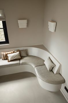 a corner bench with pillows on it next to a window