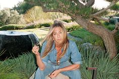 a woman sitting on a rock holding a wine glass in her hand and looking at the camera