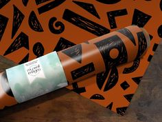 a roll of wrapping paper on top of an orange and black patterned background with arrows