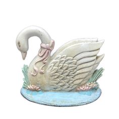 a white swan figurine sitting on top of a blue base with pink accents