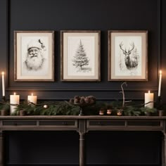 two framed pictures on the wall above a table with candles and pine cones in front of it