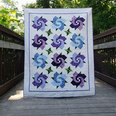 a quilt is hanging on a wooden fence