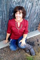 a woman sitting on the ground next to a wall