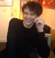 a young man smiles while talking on his cell phone