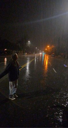 a person standing in the middle of a street at night with an umbrella over their head