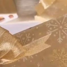 an open gift box with gold ribbon and snowflakes on the wrapping paper behind it