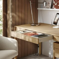 an open drawer in the middle of a desk with a cell phone and tablet on it