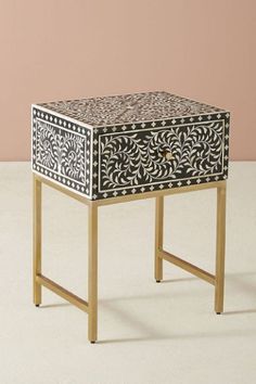 a black and white table with an intricate design on the top, against a pink wall