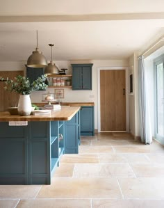 a large kitchen with blue cabinets and wooden counter tops, along with an island in the middle