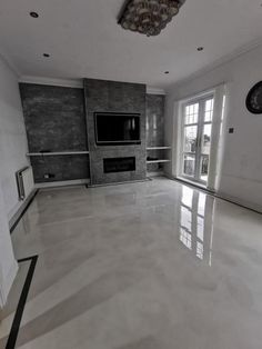 an empty living room with large windows and a flat screen tv mounted on the wall