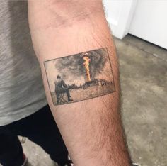 a man with a tattoo on his arm has a photo of a fire in the background