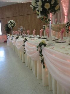 the table is set up with pink and white flowers on it for a wedding reception