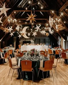 a room filled with lots of tables covered in white and black table cloths, stars hanging from the ceiling