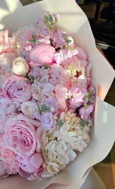 a bouquet of pink and white flowers is in the middle of someone's hand