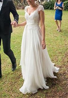 a man and woman holding hands walking in the grass with other people behind them wearing formal wear