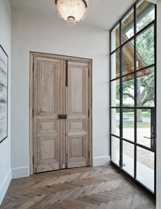 an empty room with two wooden doors and large windows on either side of the door