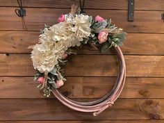 a wreath with flowers hanging on a wooden wall