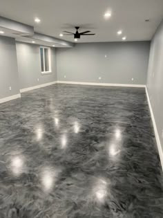 an empty room with gray walls and ceiling fans