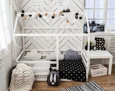 a white bed frame with black and white decor on the bottom, next to a small child's bed