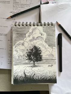 an open notebook sitting on top of a desk next to a pen and pencils