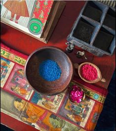 a wooden bowl filled with blue and pink colored powder on top of a colorful table cloth