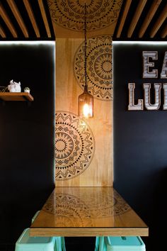 a wooden table sitting under a light next to a wall mounted sign that says eat lunch