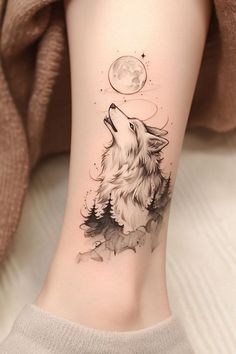 a woman's leg with a wolf tattoo on it and the moon in the background